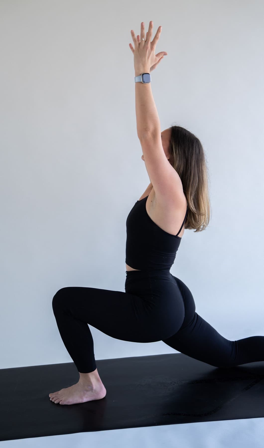 Yoga student in a grounded low lunge with one arm lifted